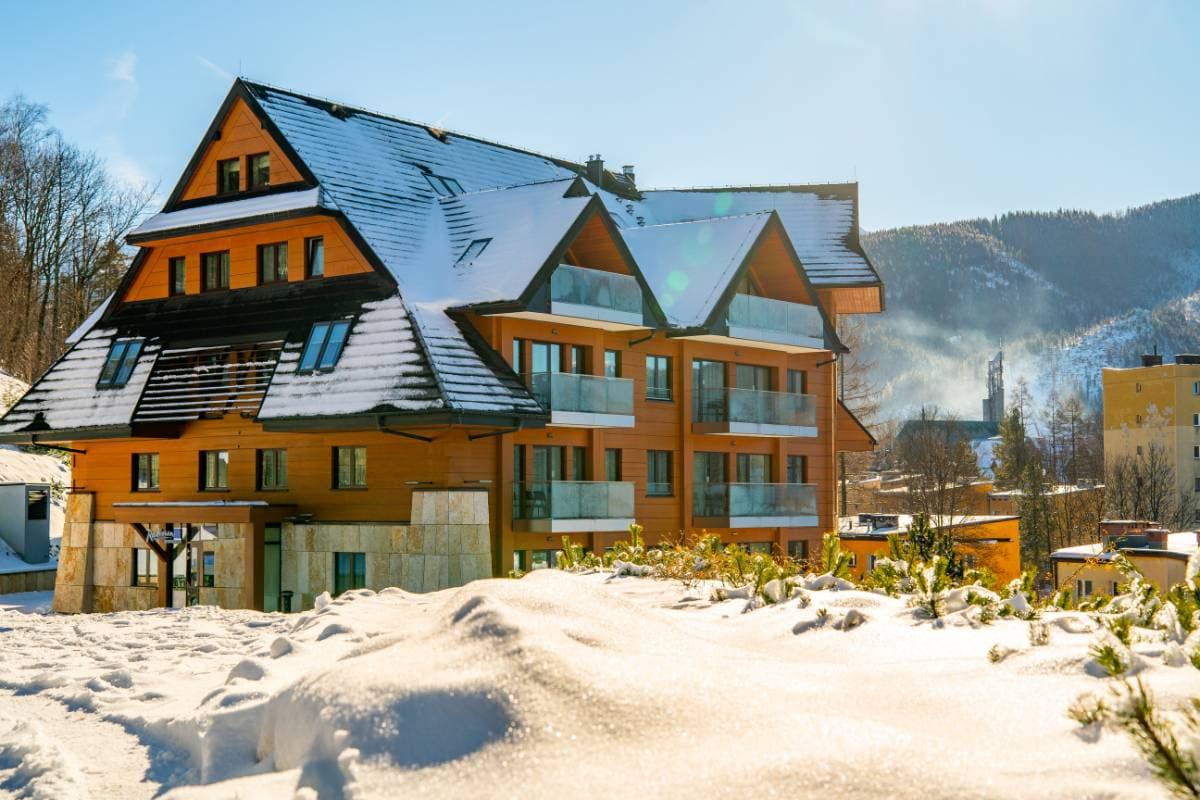 Radisson Residences Zakopane — elewacja w słoneczny zimowy dzień z drewnianą okładziną i balkonami ze szklanymi balustradami